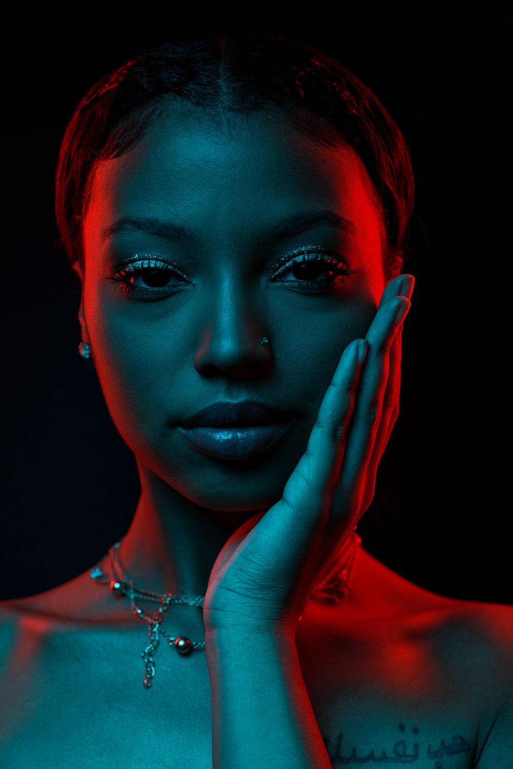 Dramatic beauty portrait with red and blue lighting creating striking contrast.