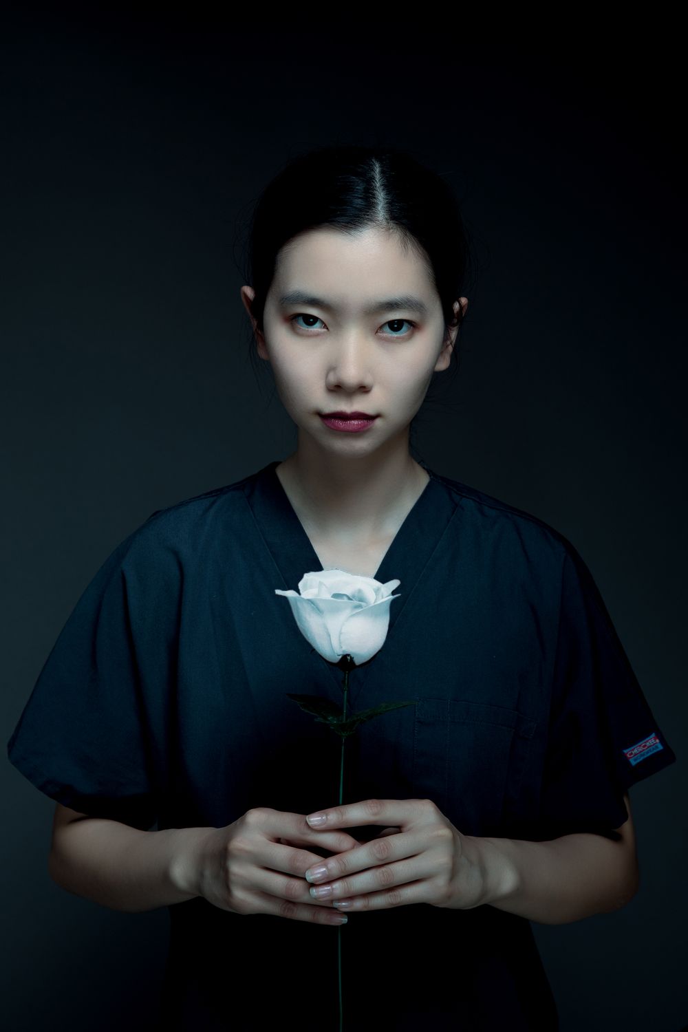 Dramatic portrait with white rose against dark background.