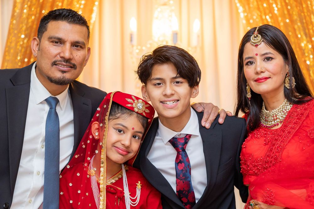 Formal family portrait with traditional and western attire against golden backdrop.