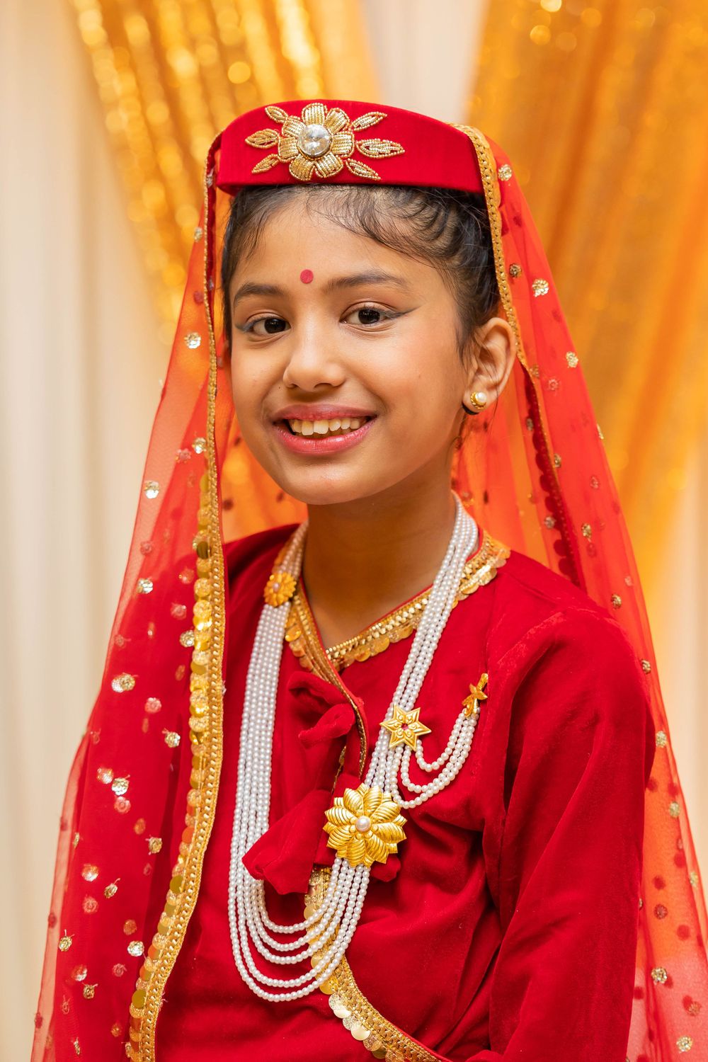 Close-up of traditional red and gold ceremonial attire with pearl and gold jewelry.