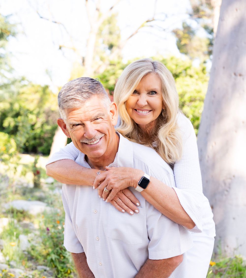 Playful couple enjoys a piggyback moment outdoors in a natural garden setting.