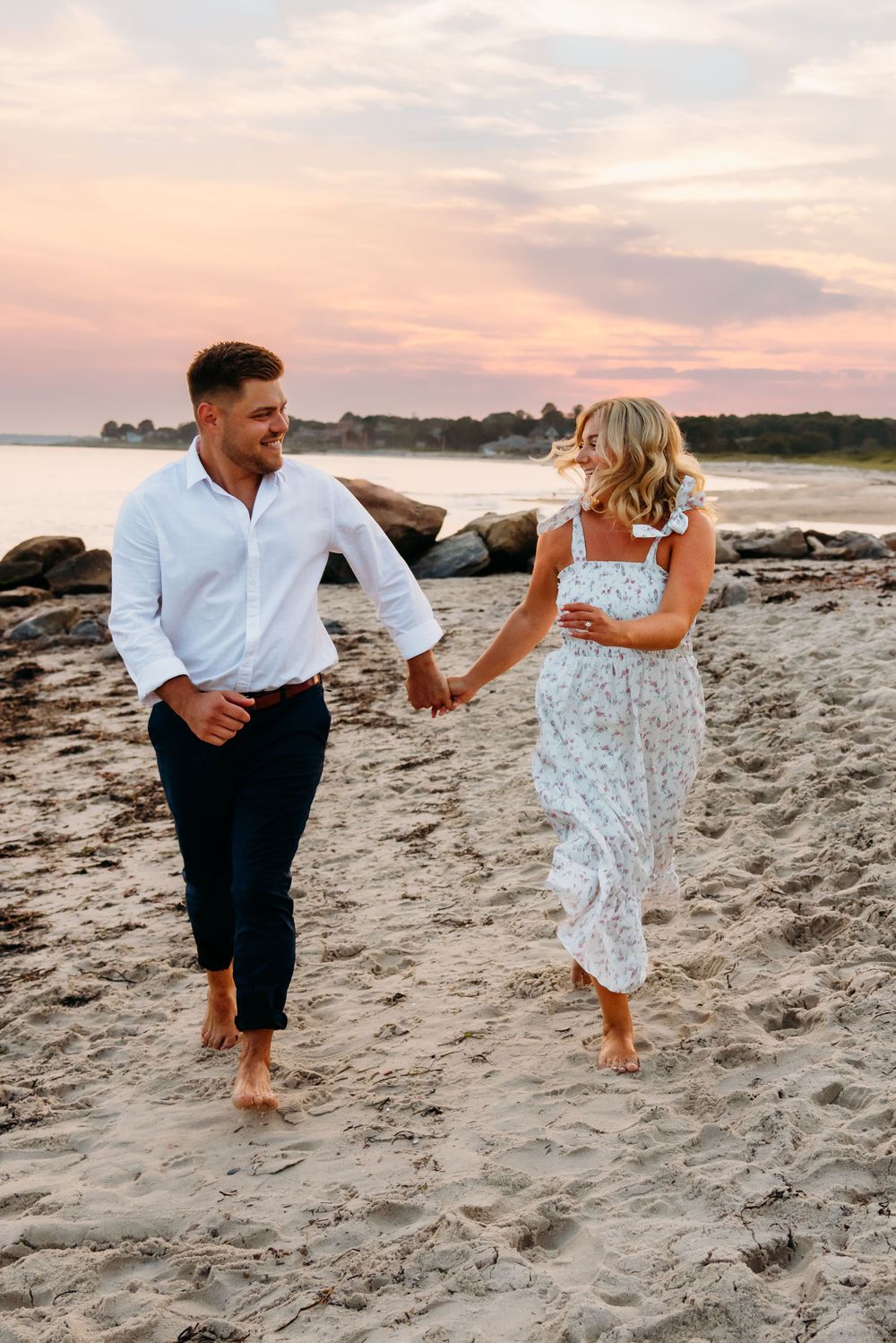 Romantic beach photoshoot of couple running barefoot in the sand during golden hour.