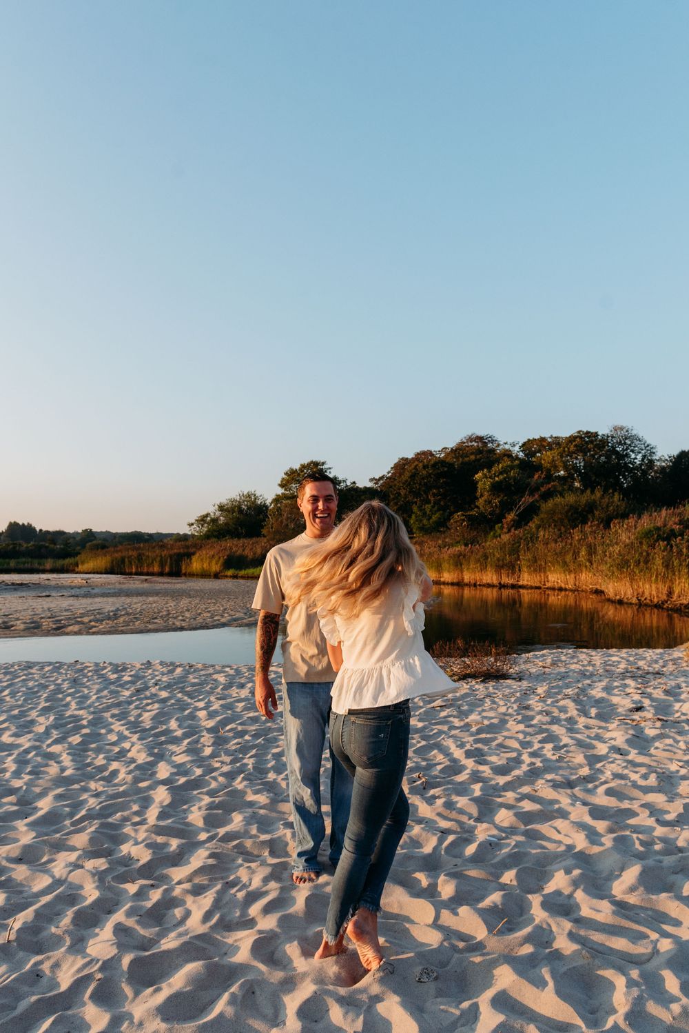 A joyful moment captured on a beach as a couple laughs together during golden hour.
