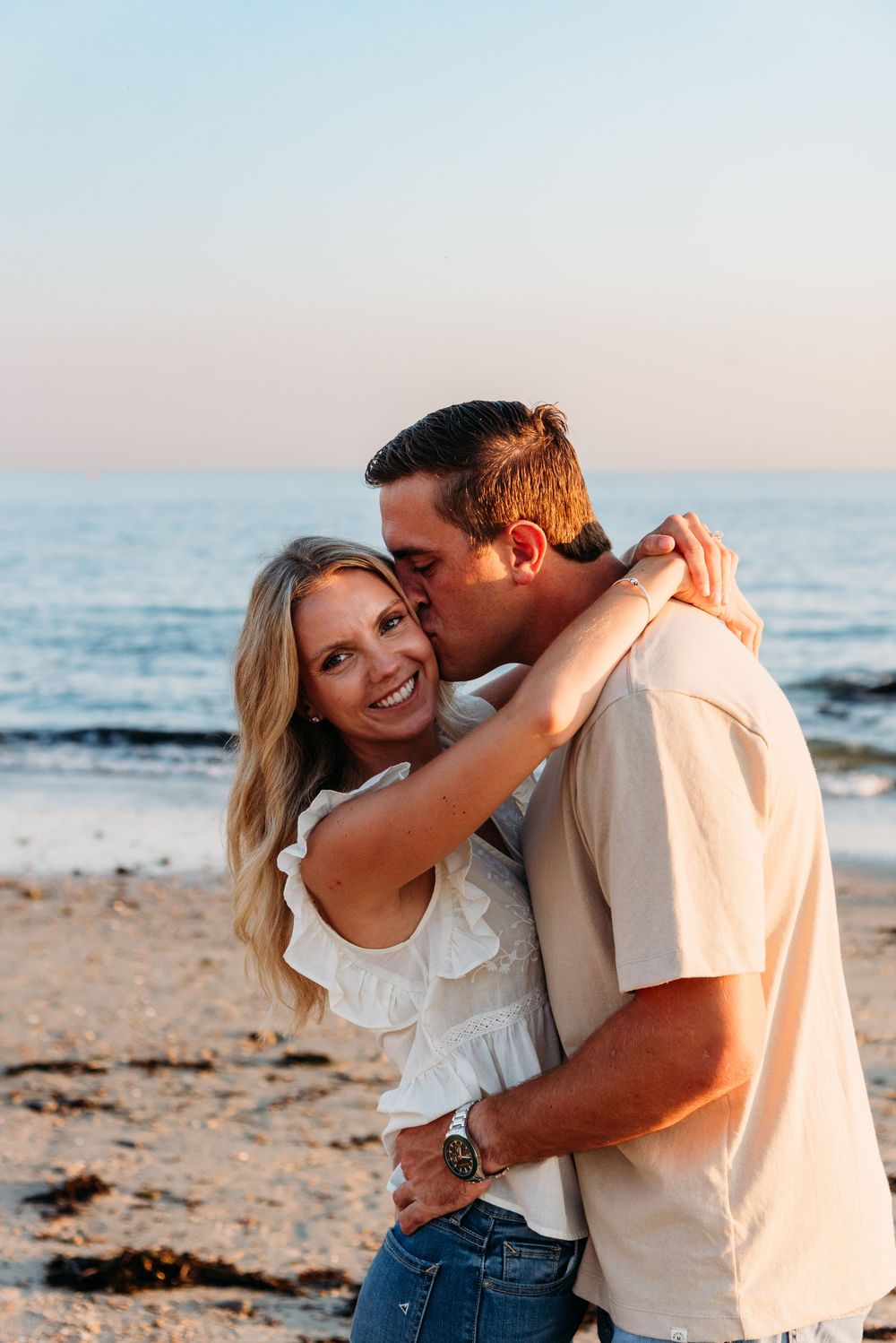 A tender beachside moment during sunset with waves crashing in the background.