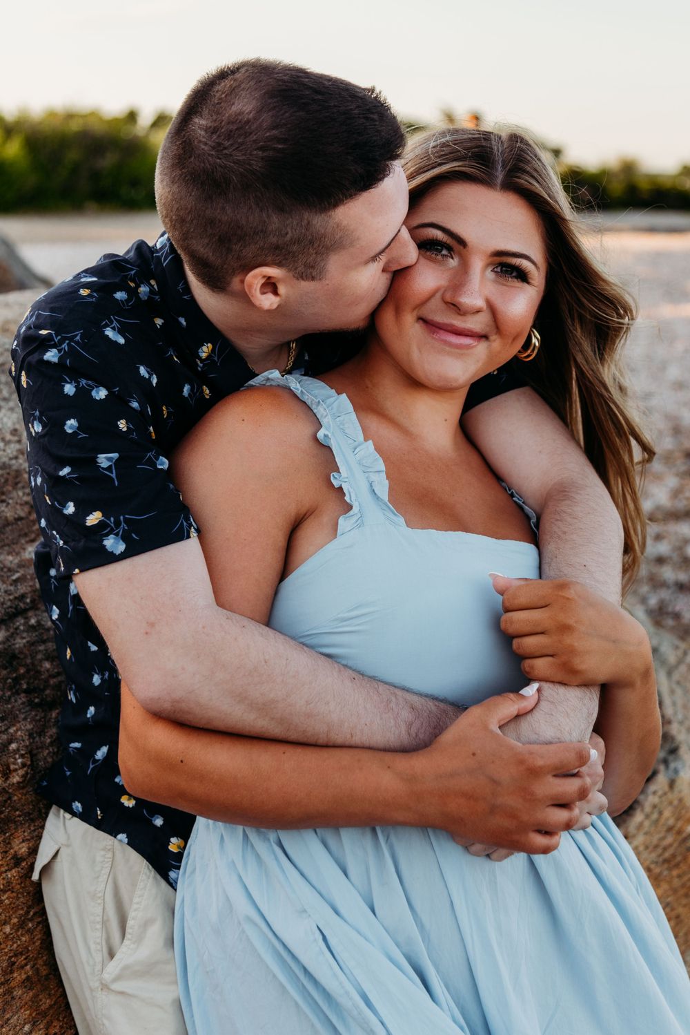 A romantic sunset portrait of a couple embracing in casual summer attire.