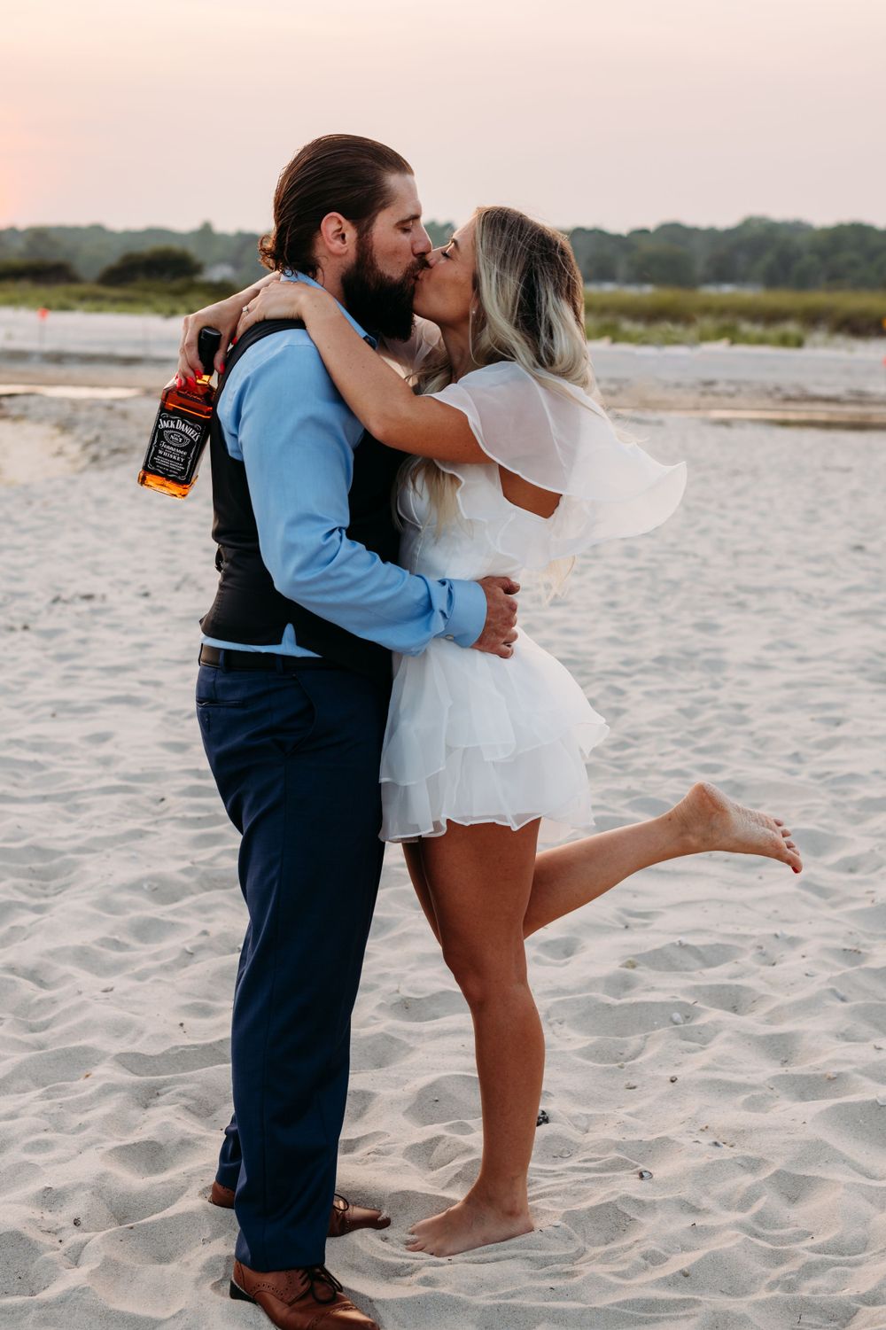 A romantic moment on the beach at sunset with a bottle of wine.
