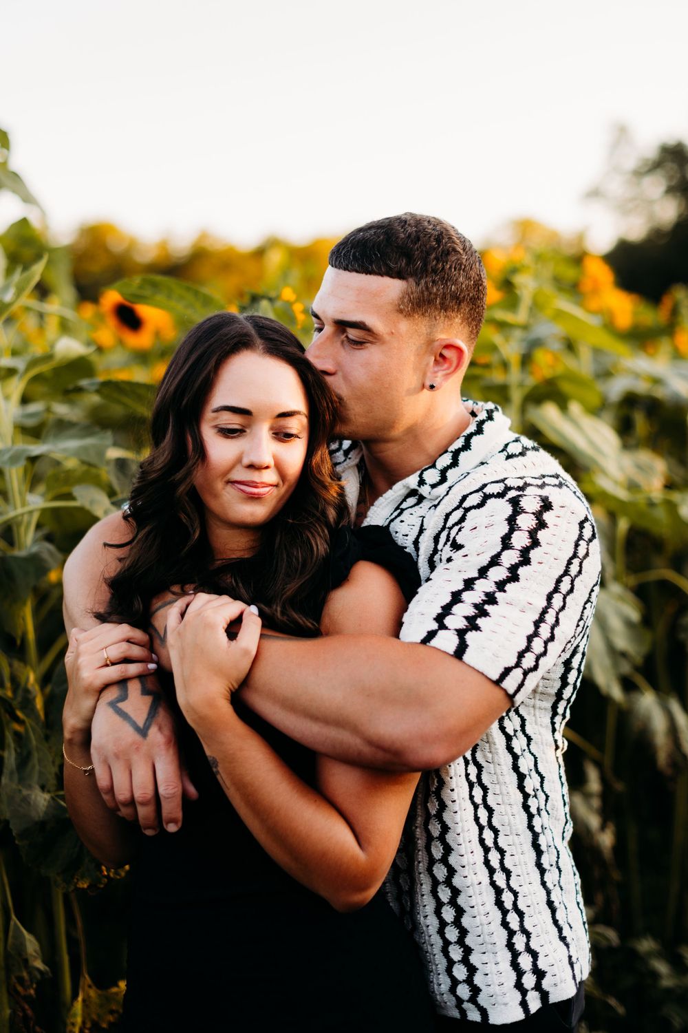 A loving embrace among blooming sunflowers during golden hour.