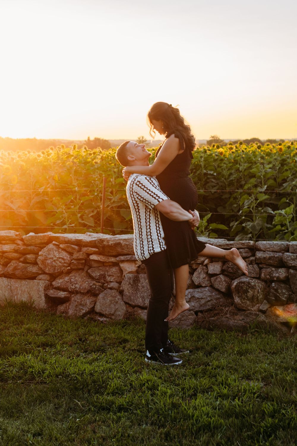 A romantic silhouette against the setting sun by a stone wall and cornfield.