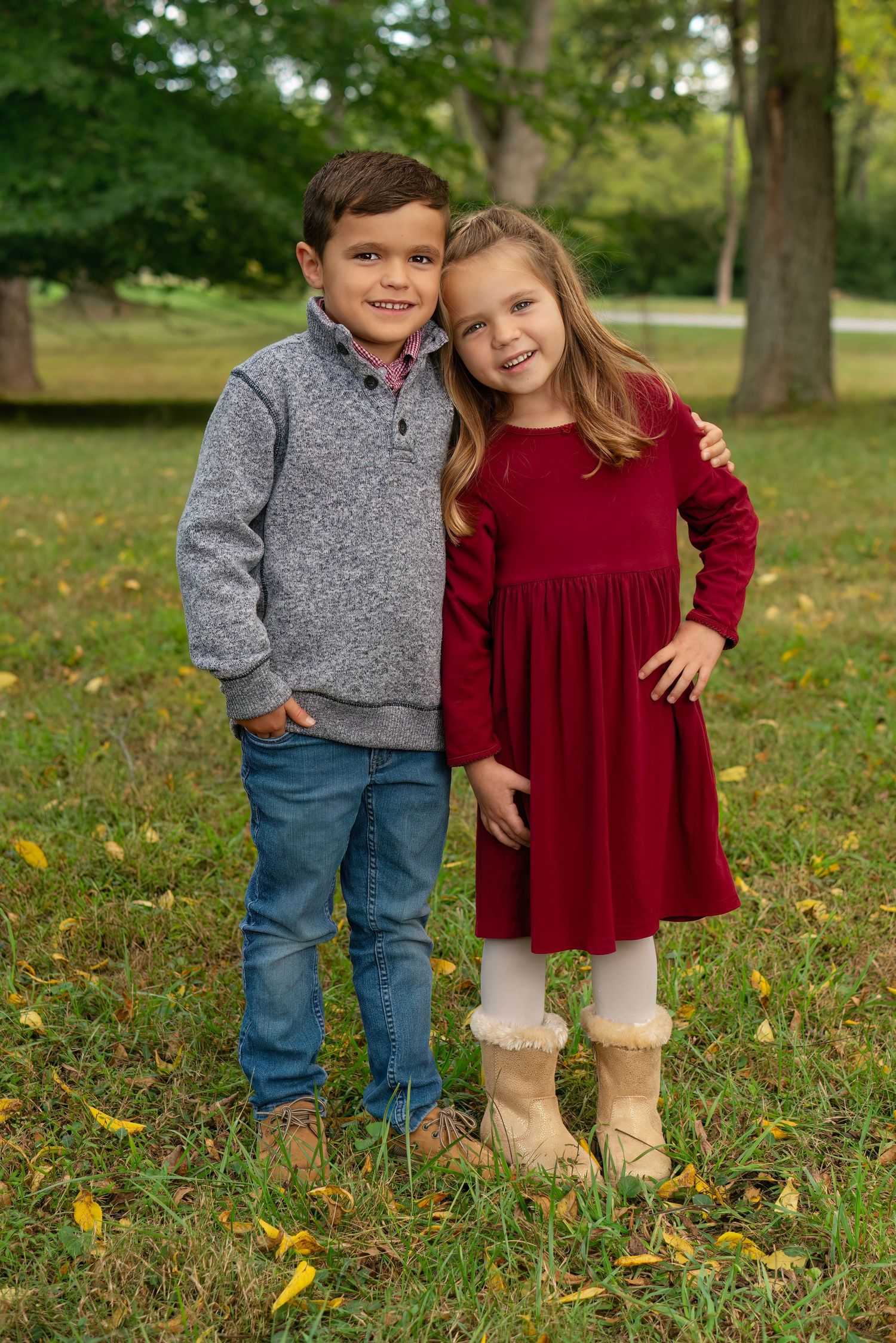 young girl rests her head on her brother's shoulder in outdoor photo