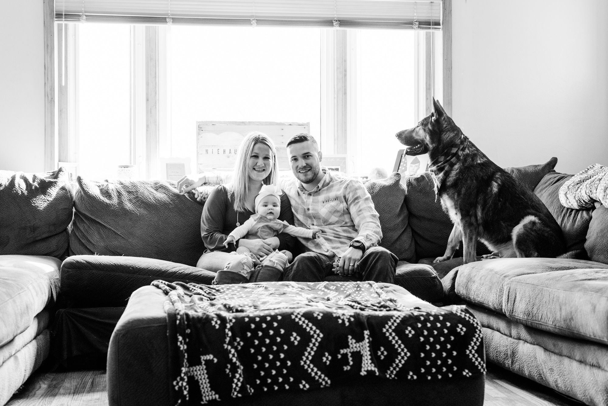 Lifestyle family photoshoot in the home with mom, dad, baby, and dog sitting on couch in Gibsonia, Pennsylvania