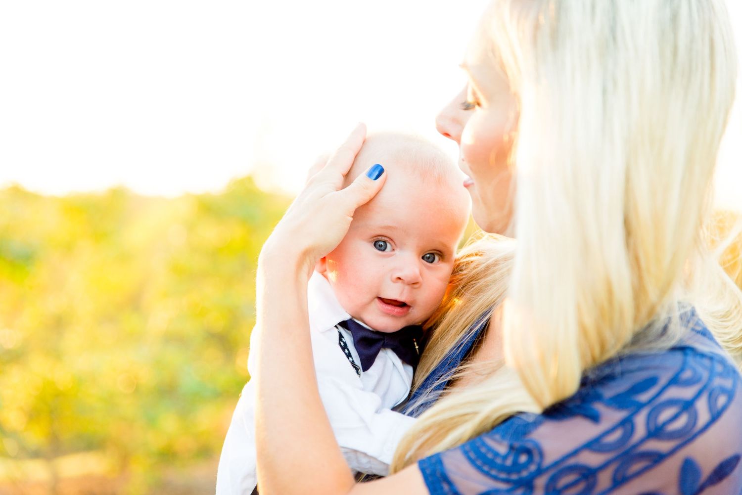 woman with long blonde hair holds her baby boy to her chest at sunset in Grant Park