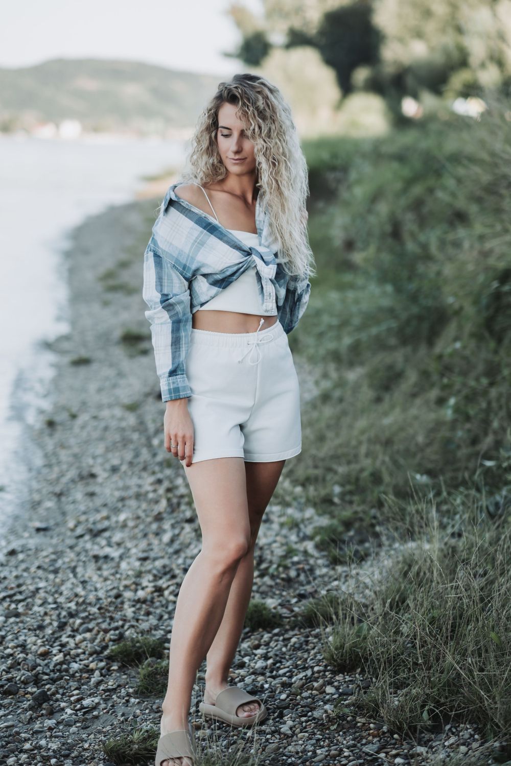 Casual summer outfit featuring denim jacket and white shorts photographed near waterfront.