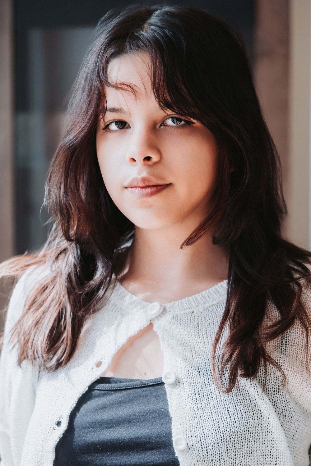 Portrait of person wearing white knit cardigan in natural window light.