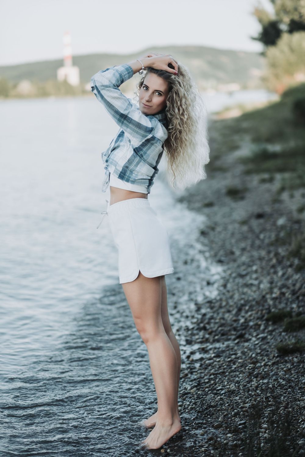 Fashion portrait at waters edge wearing cropped denim jacket and white shorts.