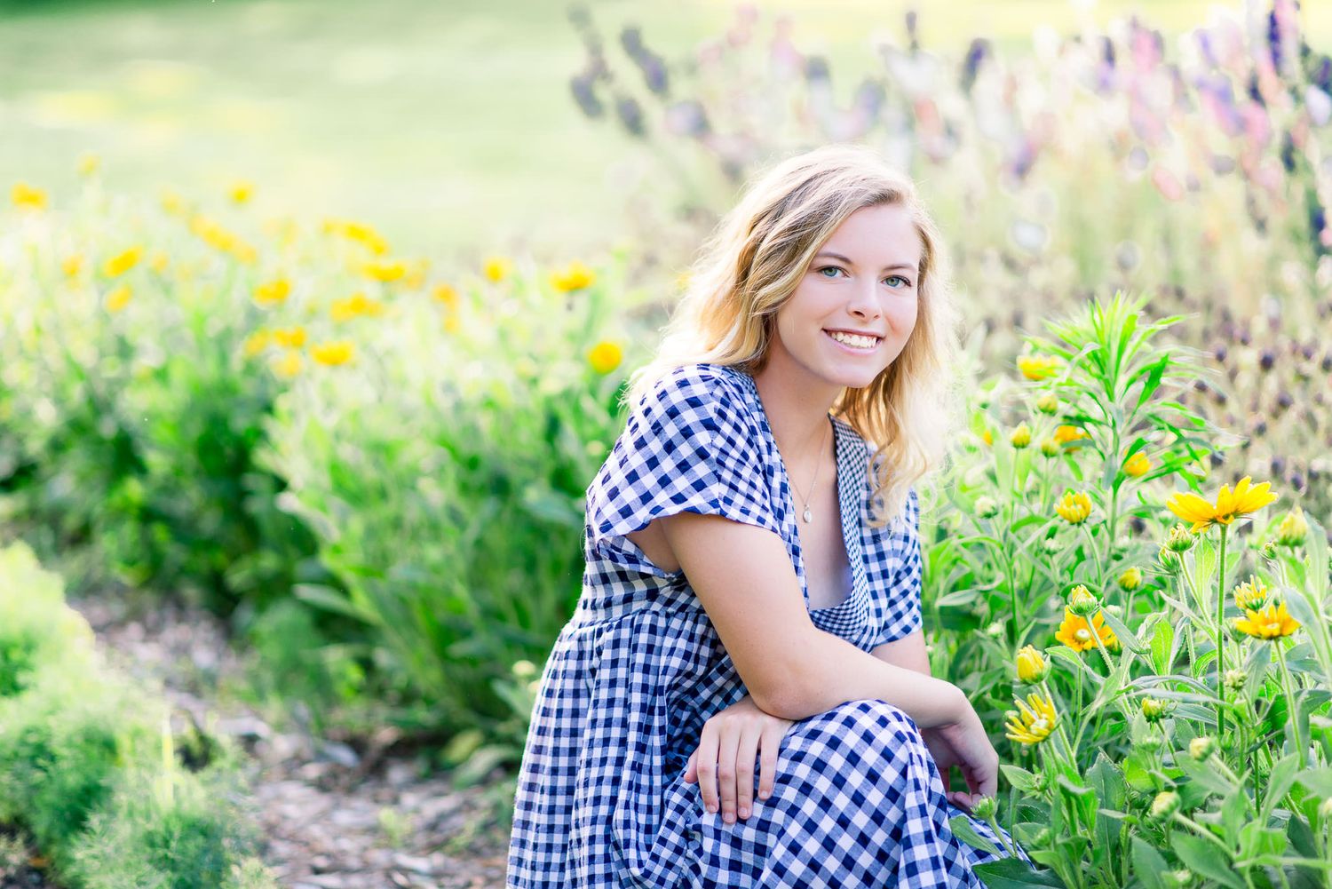 young woman with blonde hair smiling and crouching by yellow flowers at The Marmalade Lily