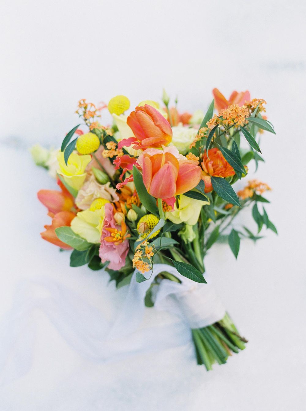 A vibrant bouquet of orange and yellow flowers resting on a pristine white surface.