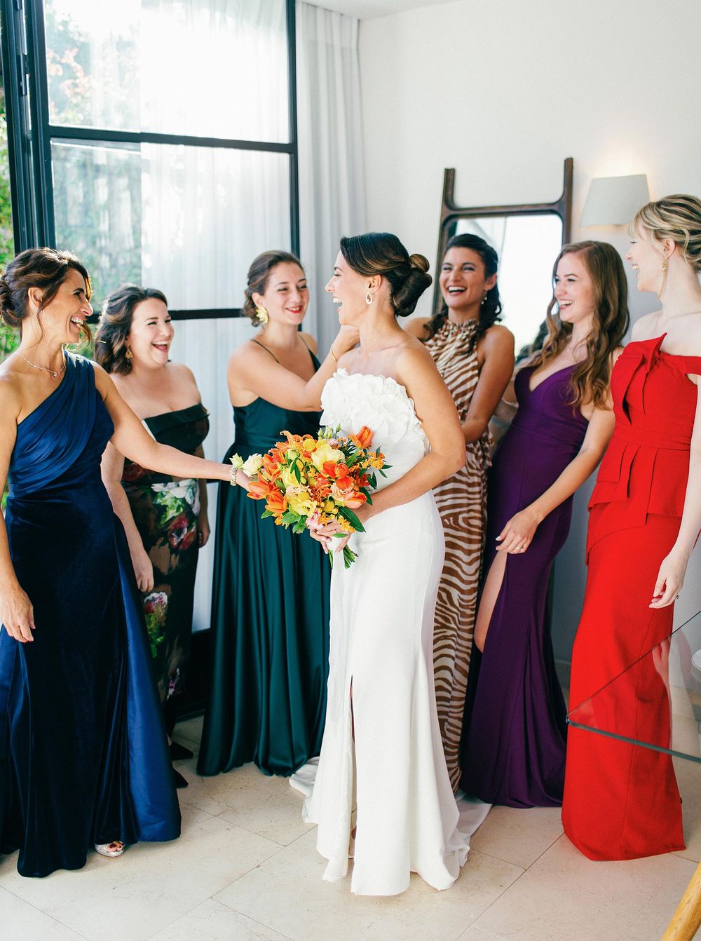 Bridesmaids in vibrant dresses, bride holding a bouquet, getting ready in Villa La Coste, Provence.