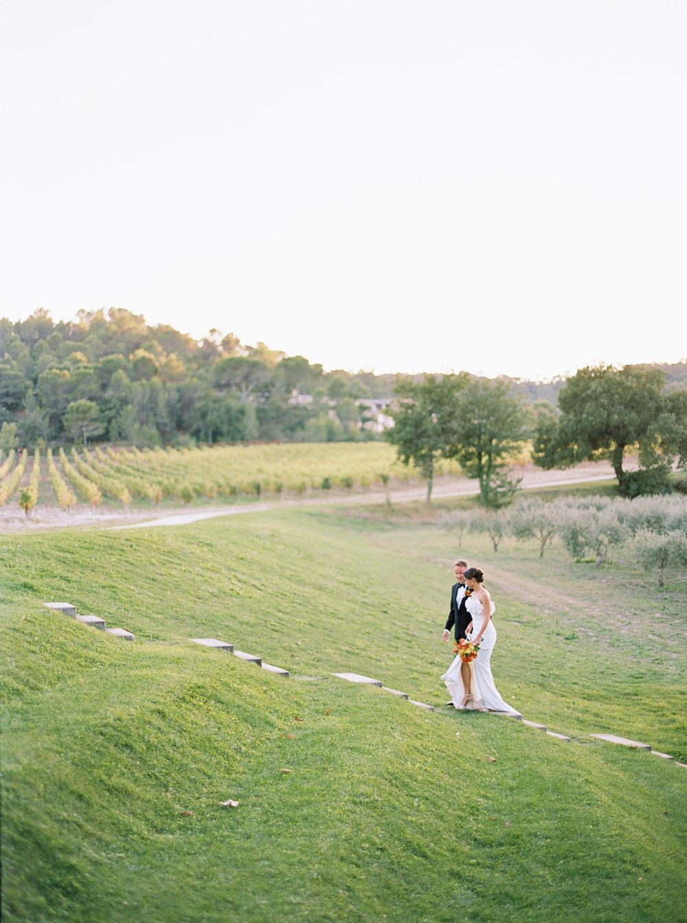 Bride and groom walking together in a picturesque winery, Château La Coste, Provence.