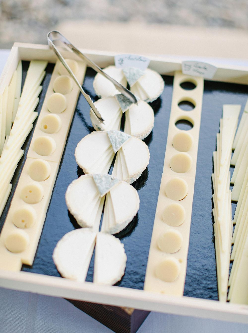 A platter of assorted cheese slices and cheese cutters, perfect for a cheese lover's delight.