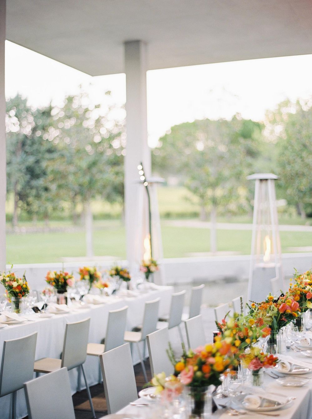 Elegant table setup at Château La Coste, Provence, featuring white linens and orang floral for a wedding reception.