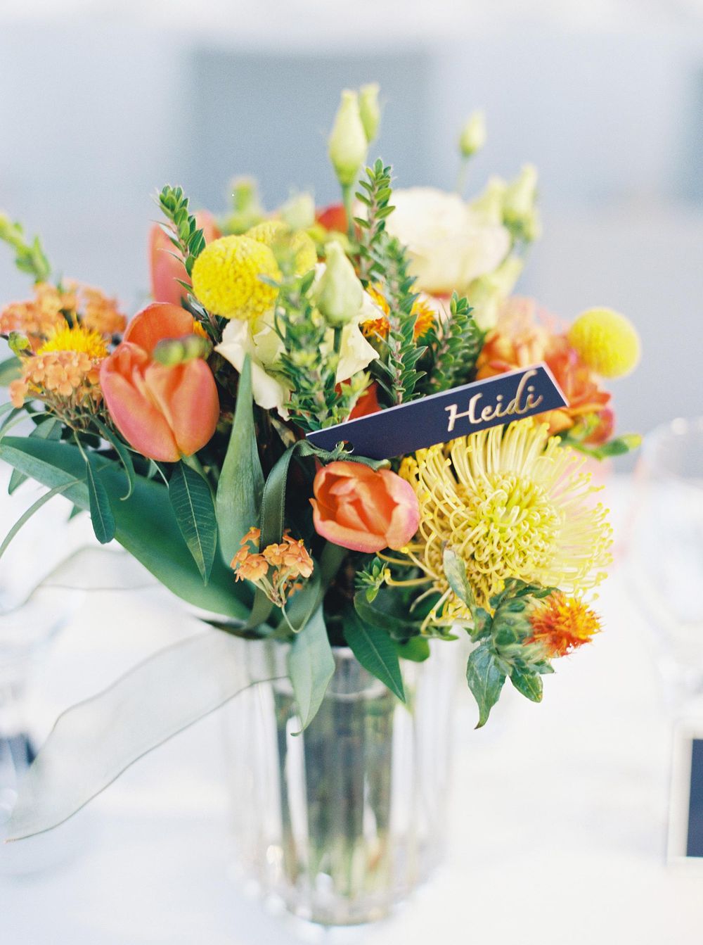 A vase with vibrant orange and yellow flowers on wedding table in Provence.
