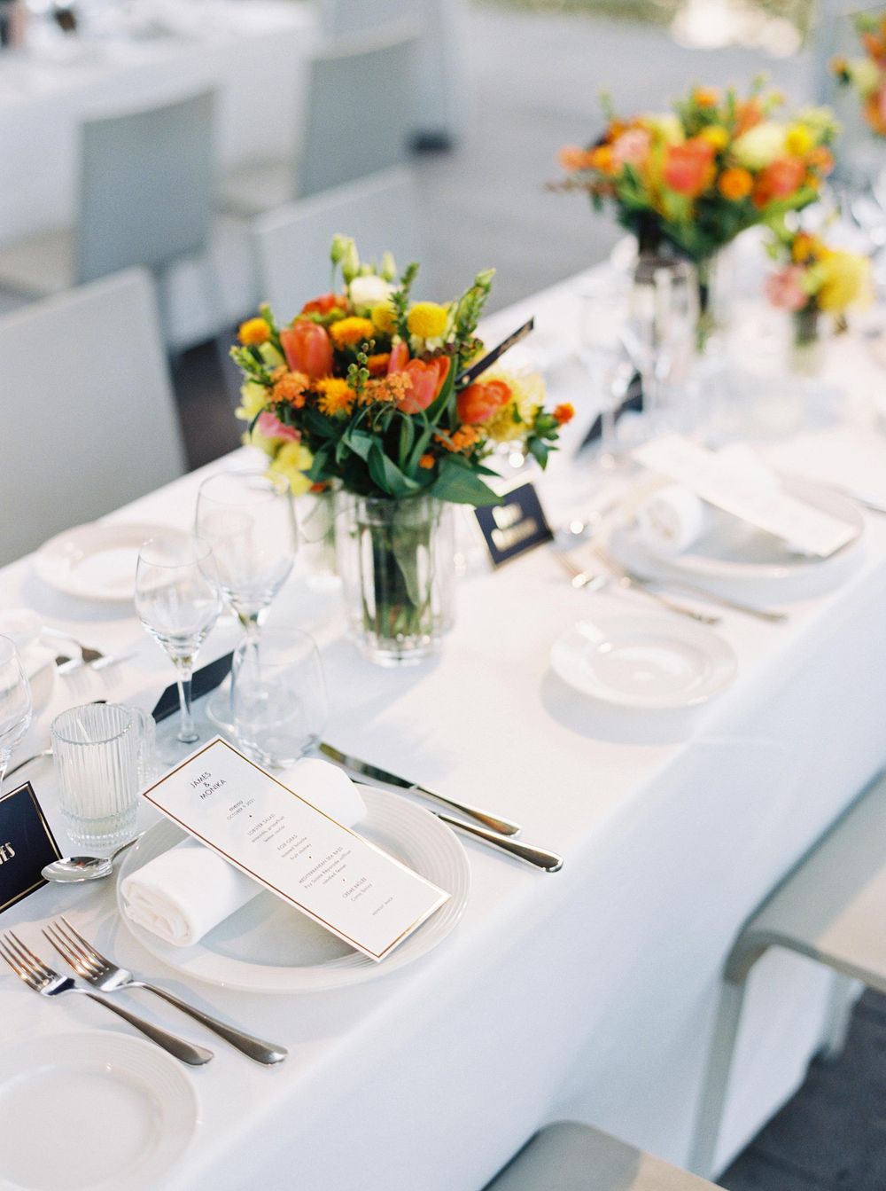 A beautifully decorated wedding reception table at Château La Coste, with white linens and vibrant orange flowers.