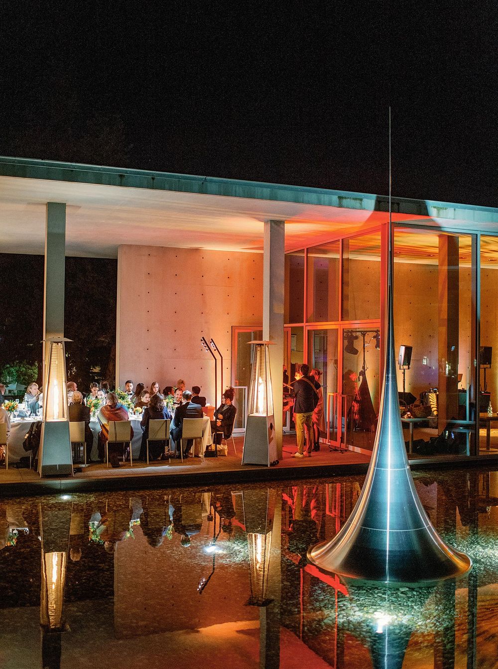 Wedding reception at Château La Coste, Provence: people dining at tables with a stunning fountain.