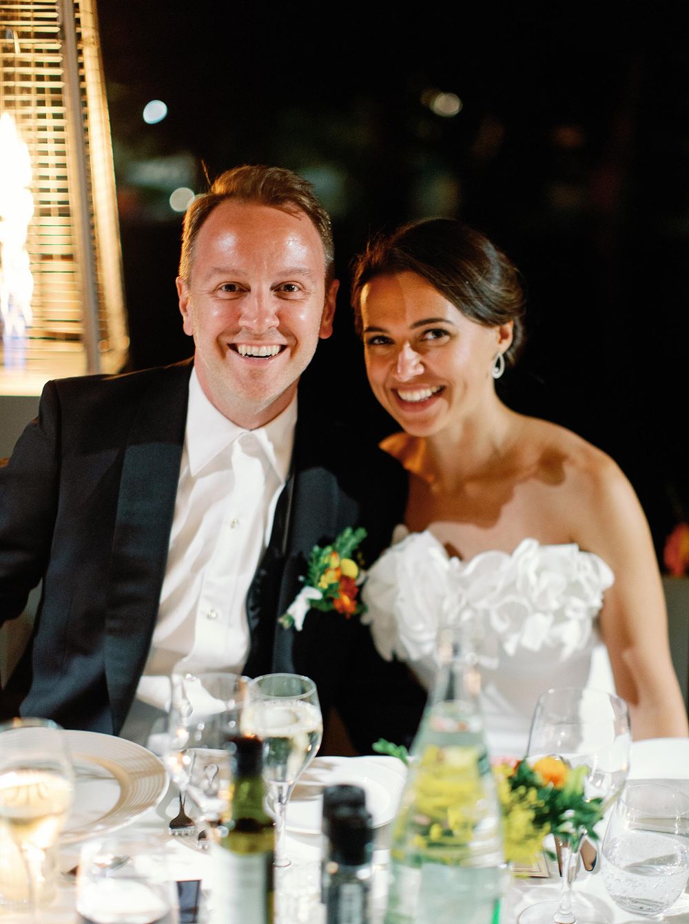 Newlyweds enjoying a quiet moment at their reception, seated together at a beautifully decorated table.