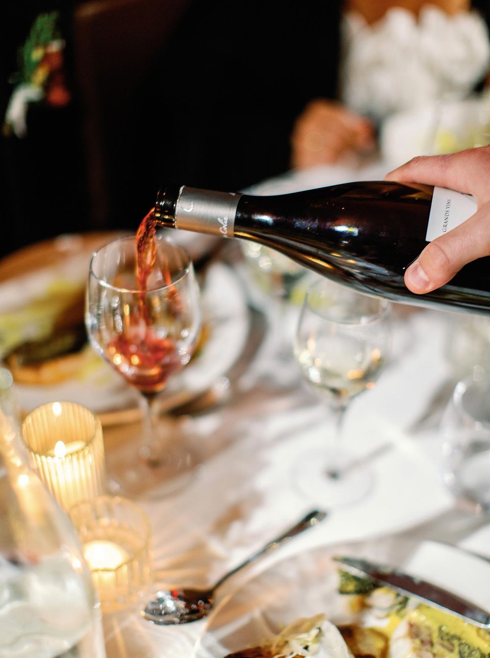 A person gracefully pouring wine into a glass, creating a delightful and elegant ambiance.
