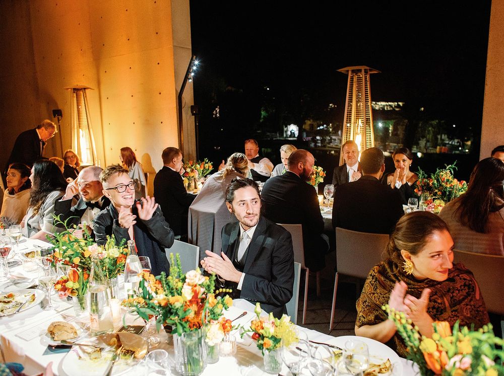 A wedding reception with a group of people sitting at a table, enjoying the celebration.