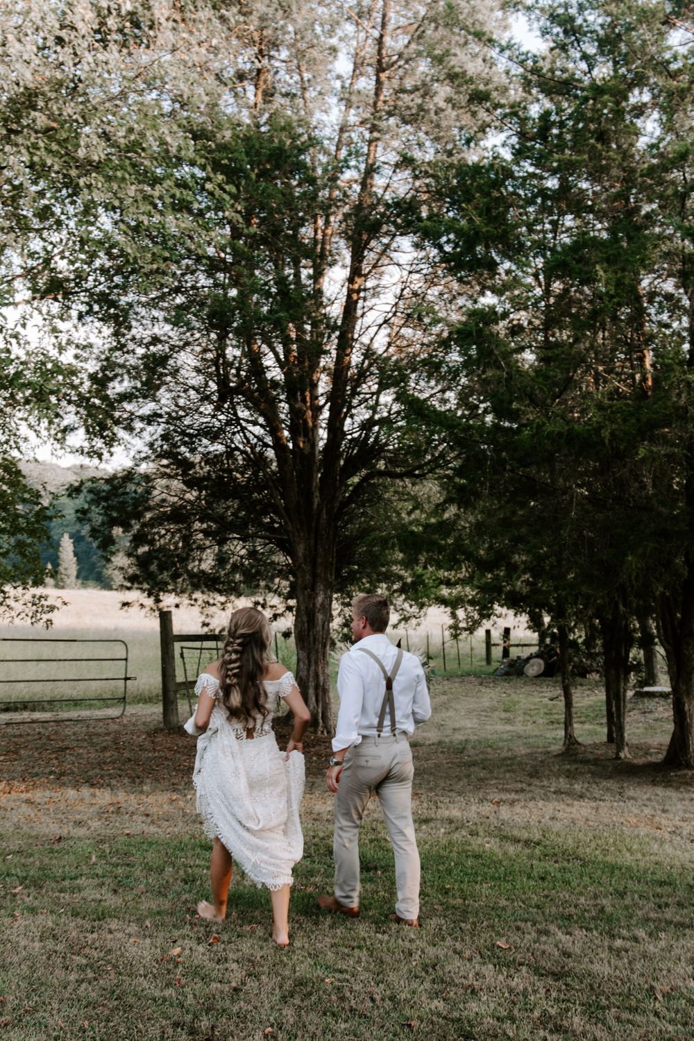 woman hiking up her wedding dress walking towards a field with her new husband during their full day Tennessee elopement