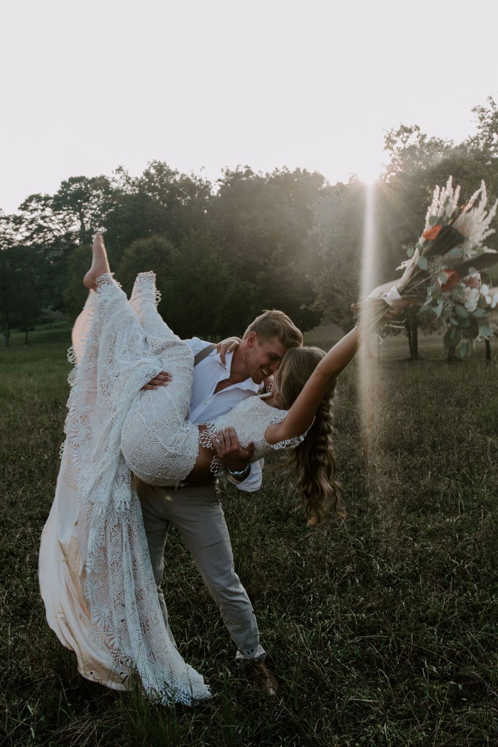man dipping his new wife while she throws her bouquet in the air during their full day elopement