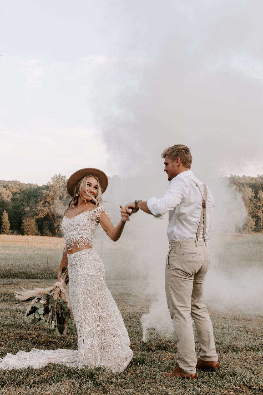 man twirling his new wife as she is holding her bouquet with a smoke bomb going behind them