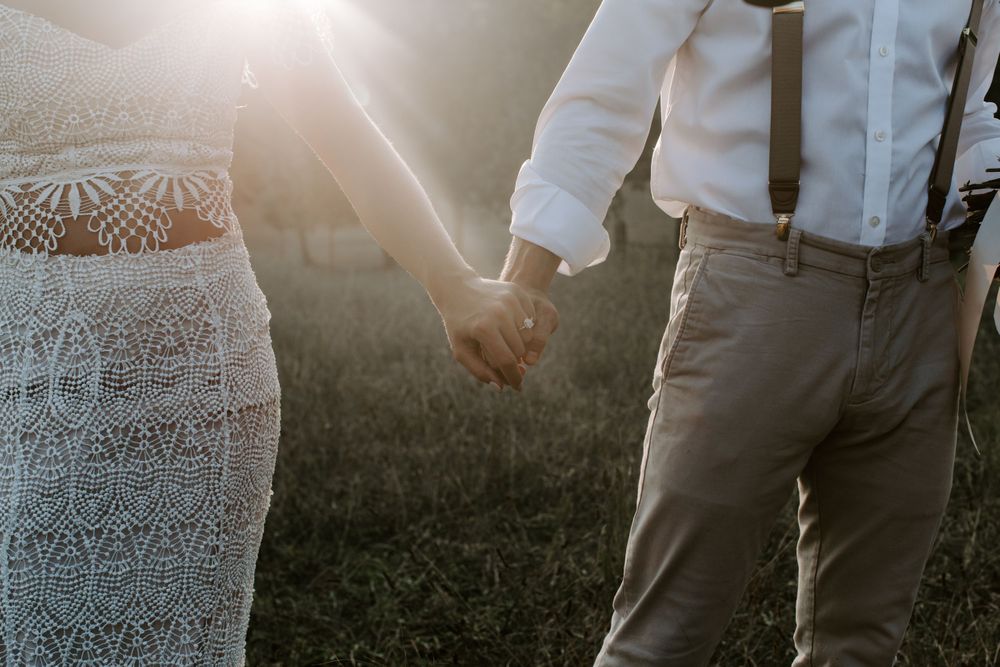 couple holding hands walking through a field during their Tennessee wedding
