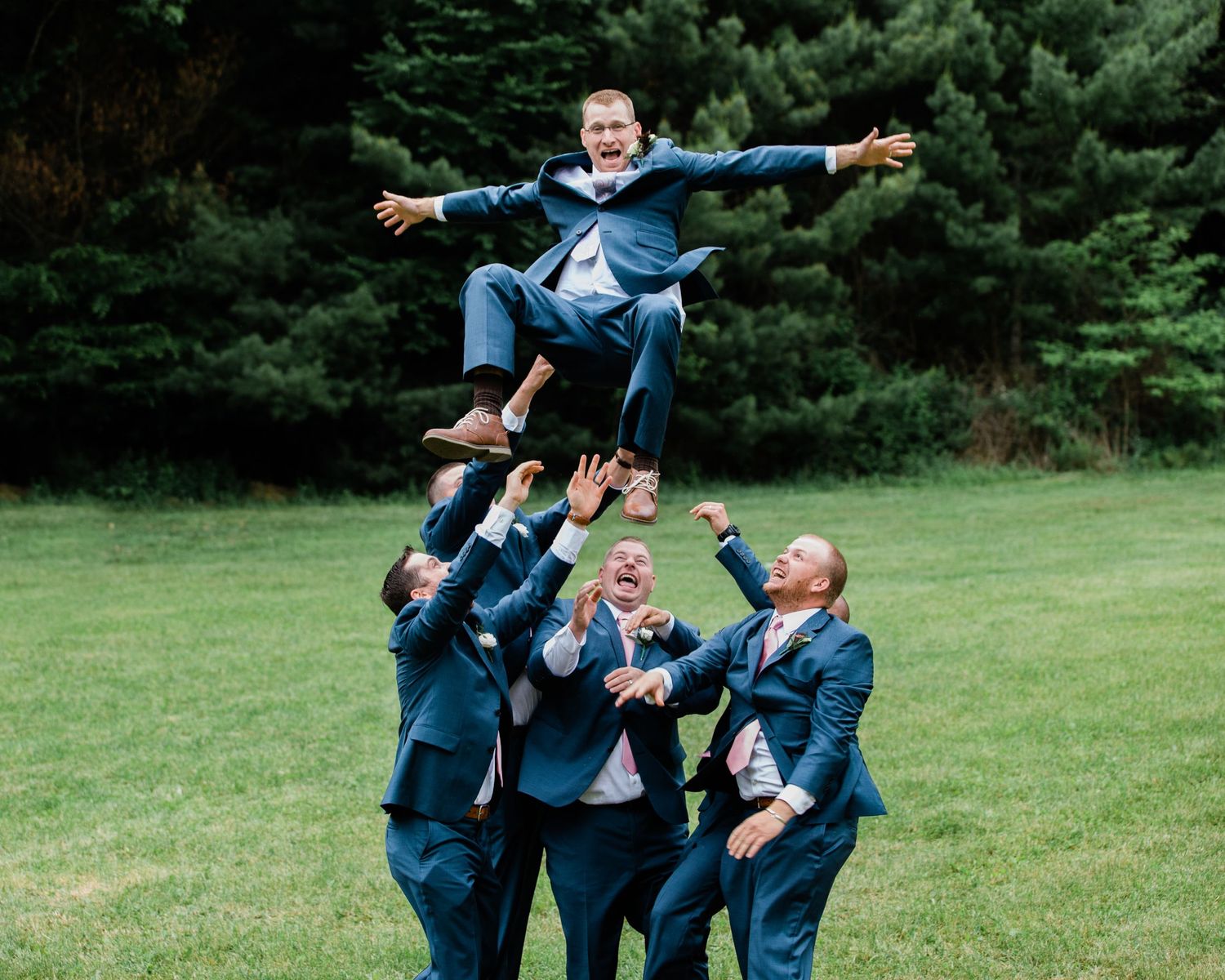 Groomsmen toss groom up in the air