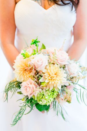 bride holding pastel yellow, pink, and neon green wedding bouquet for a fall or spring wedding