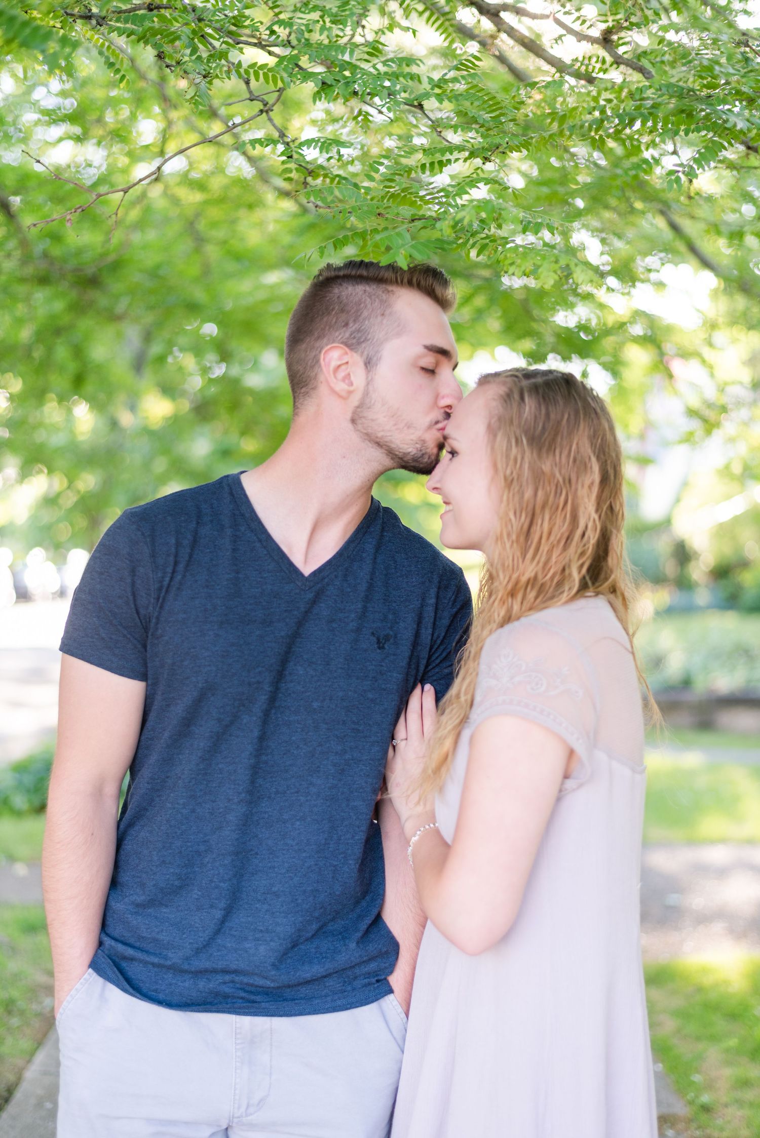 Boy kissing girl's forehead on sidewalk for engagement in Franklin Pennsylvania