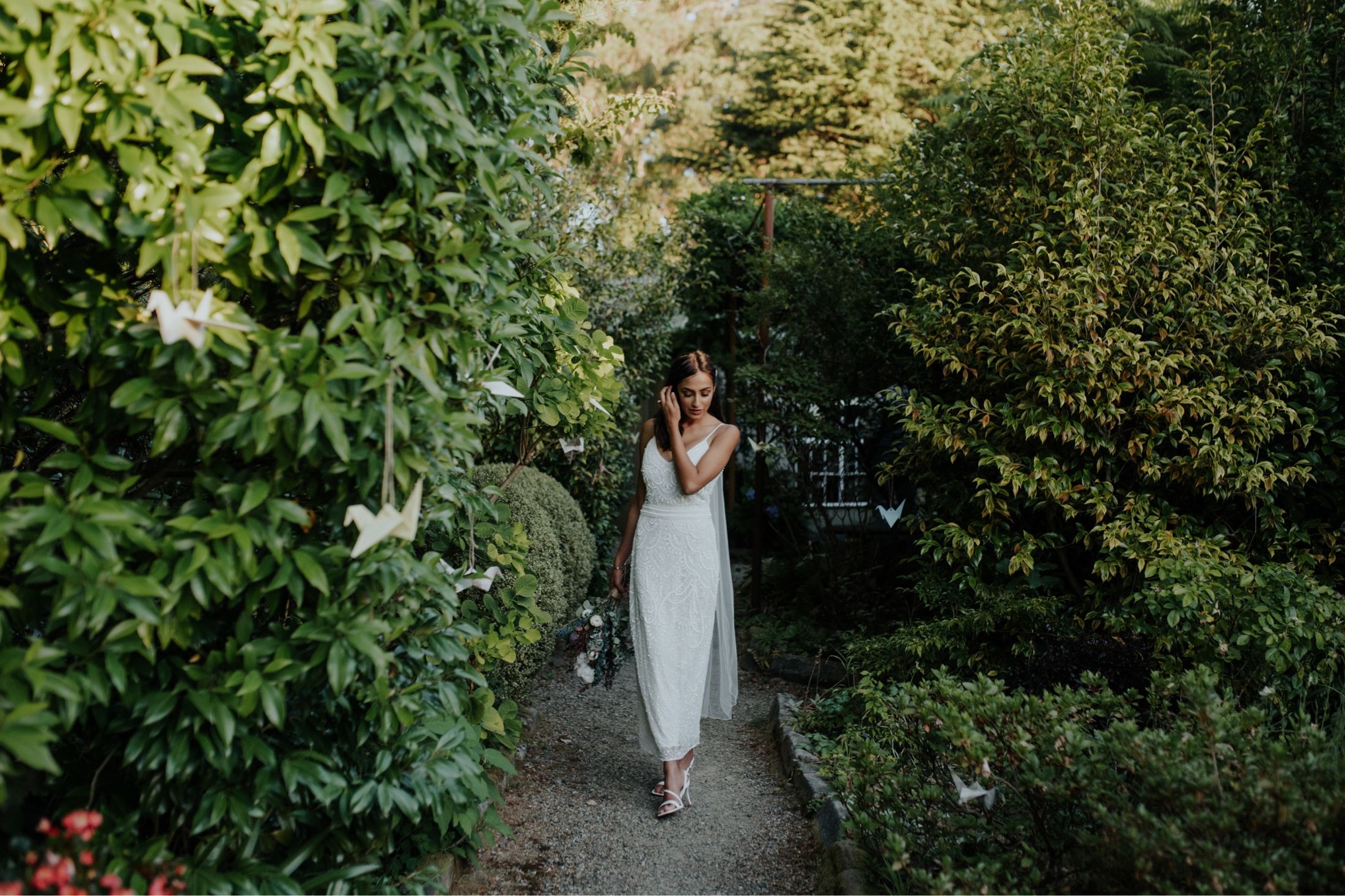 Bride walking down garden path at Fortnums Sassafras with origami cranes lining trees