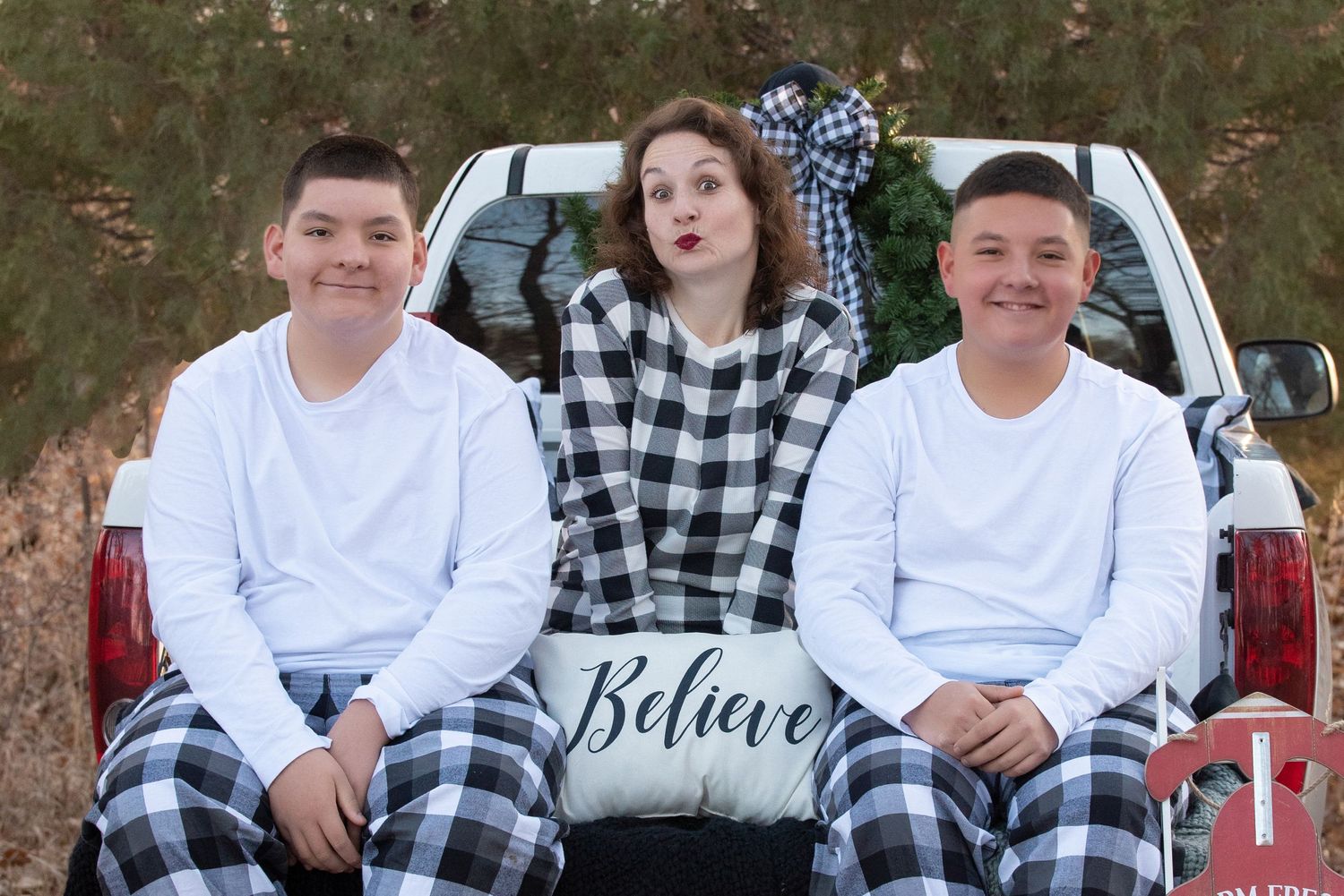 Mama and her 2 boys during their Christmas session in black and white buffalo plaid on a white truck