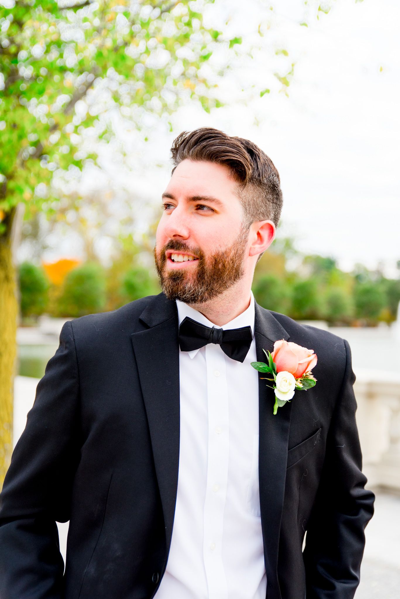 brunette groom with beard in black suit and bowtie smiles off to the side for St. Louis fall wedding
