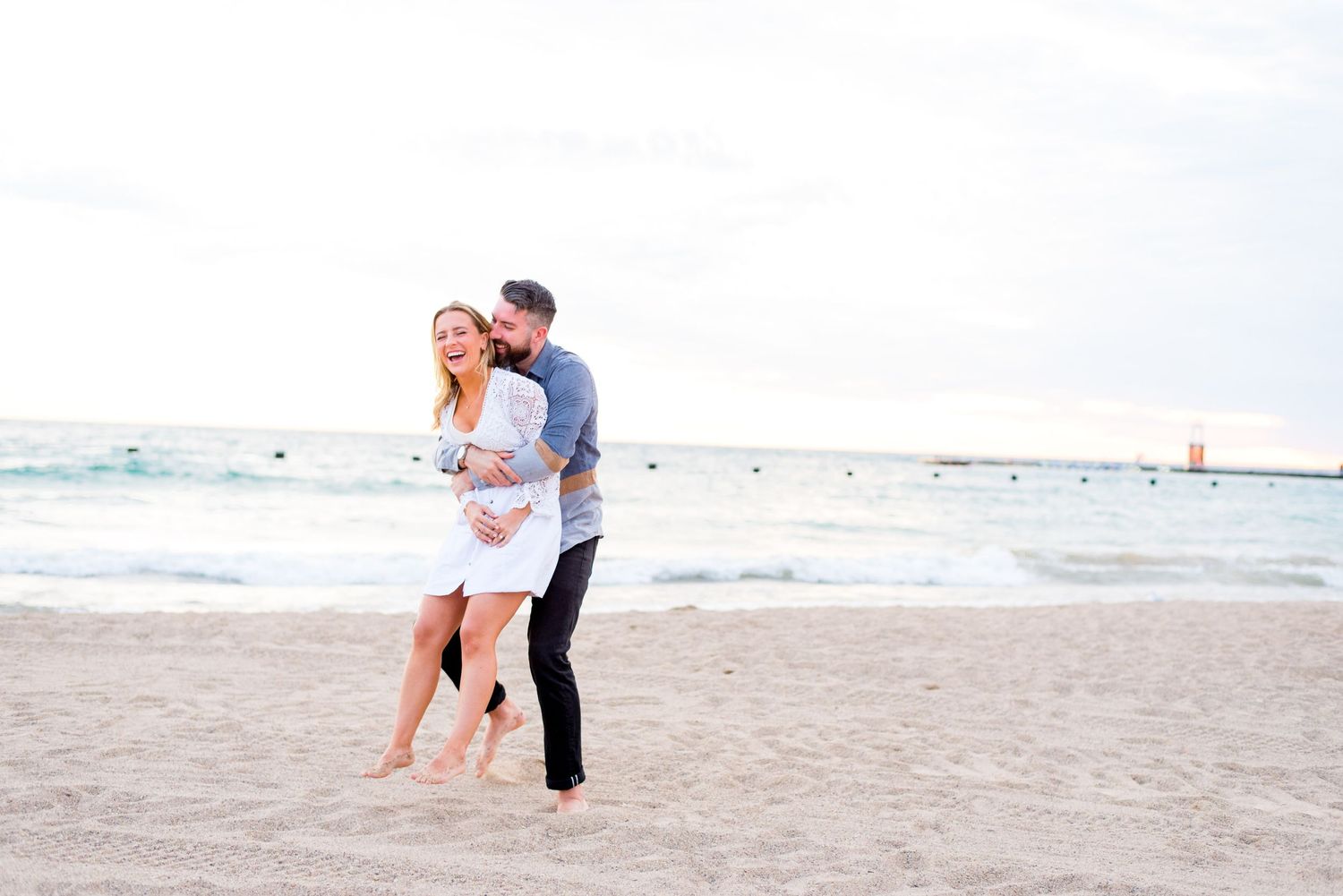 man hugs woman from behind and spins her around on North Avenue Beach during sunrise