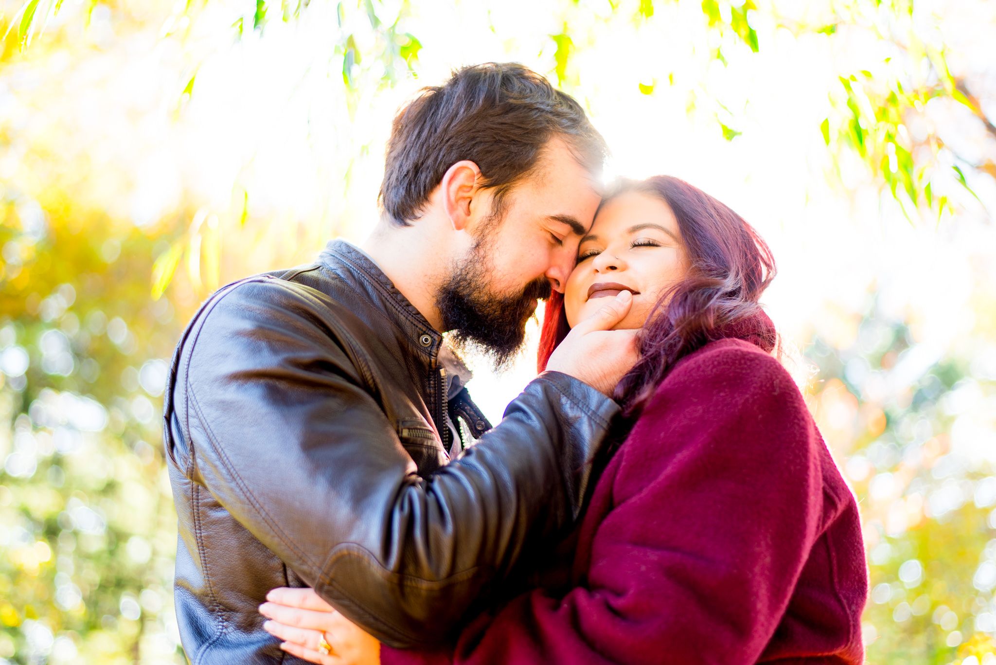brown hair man holding woman with red hair in matching red coat, smiling at sunrise in Central Park