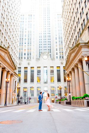man and woman spin around in front of Chicago Board of Trade at sunset on empty street in downtown Chicago