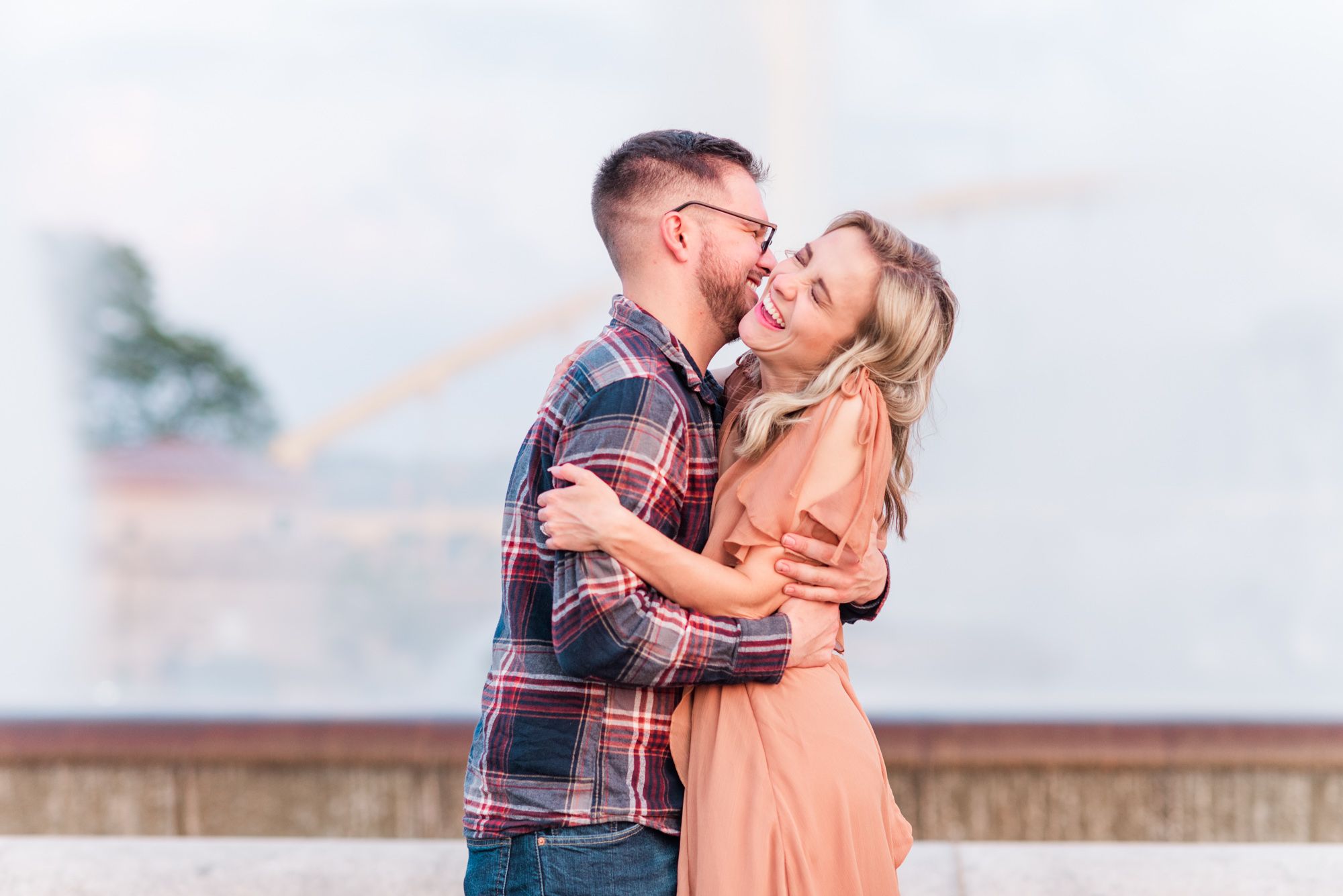 Newly engaged couple laughing in front of fountain at sunset at Point State Park in Pittsburgh, Pennsylvania