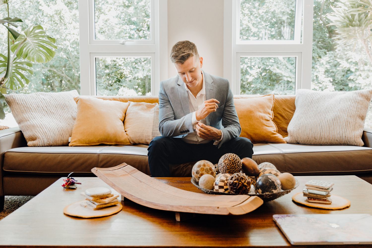 Modern living room setting with breakfast spread on curved wooden tray and orange accent pillows.
