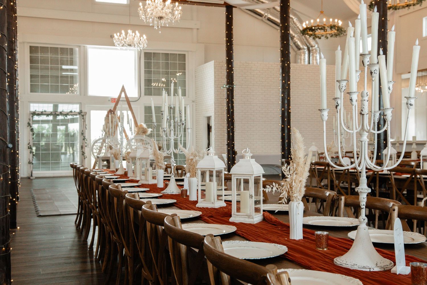 Wedding reception table setting with white candles, rustic decor and elegant place settings.