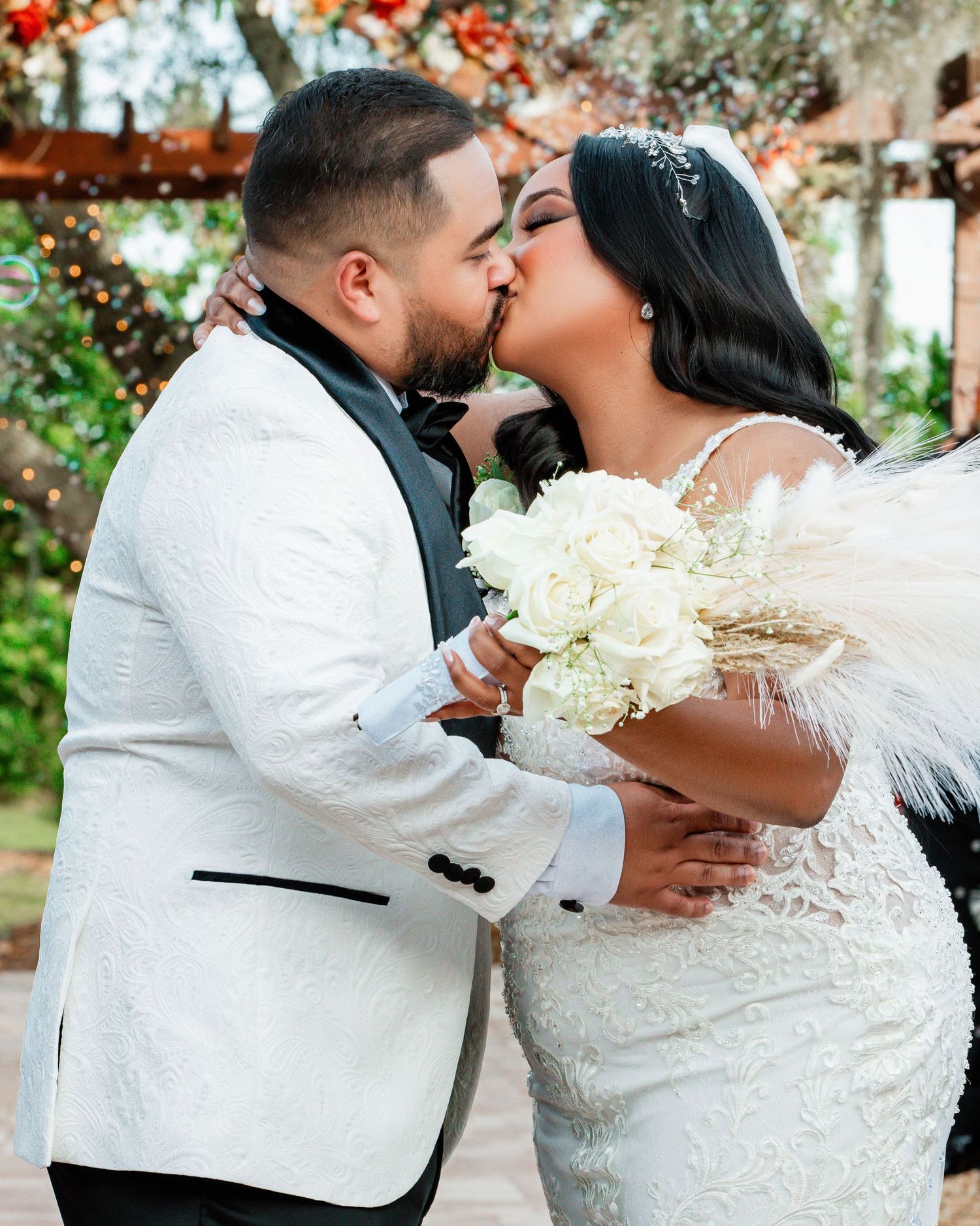 Wedding couple sharing intimate moment in garden with white floral bouquet.