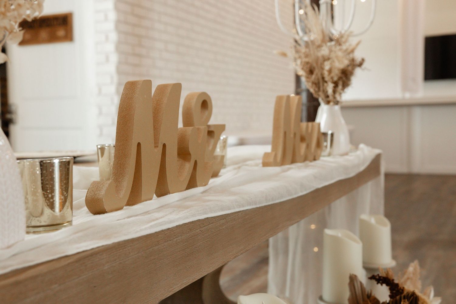 Decorative Mr and Mrs wooden letters displayed on a white table with candles.