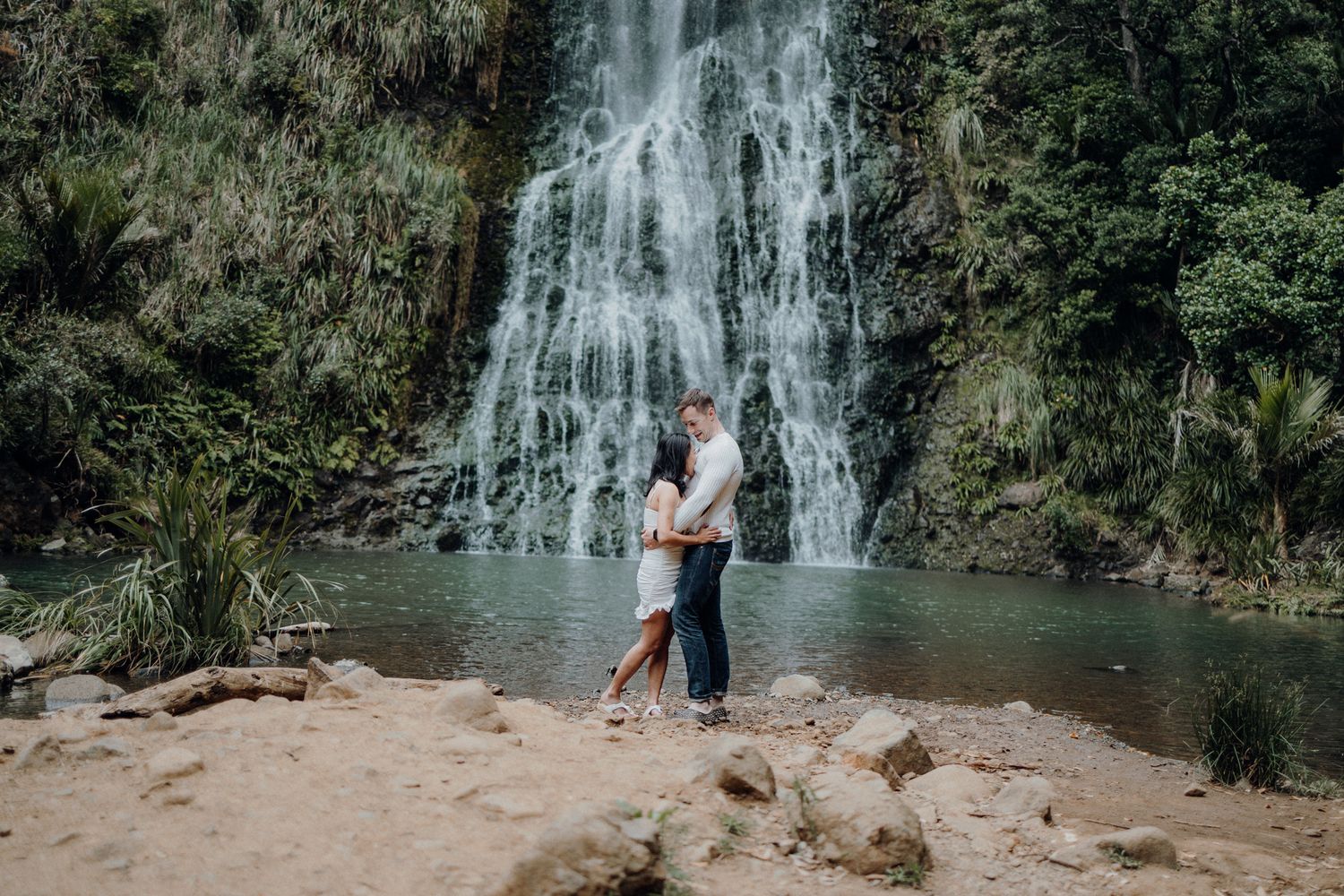 A fun couple in Karekare Falls for their post-wedding photoshoot with Apertured Media-Auckland Wedding Photographer
