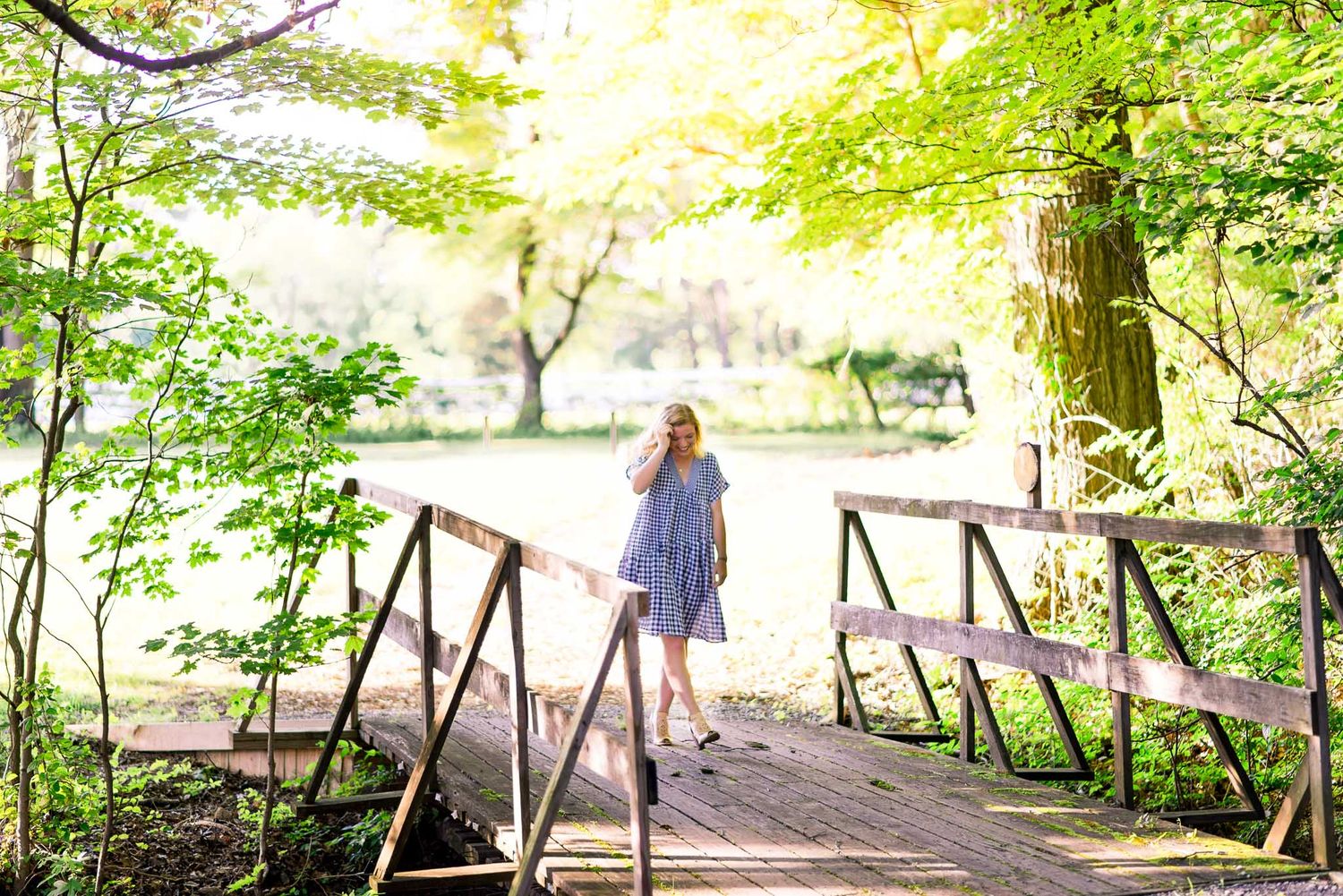 young woman walking across bridge in woods at The Marmalade Lily in Loveland Oh